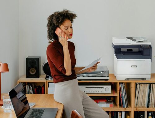 Eine Frau sitzt an einem Schreibtisch und telefoniert neben einem Xerox® C325-Drucker